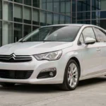 Citroën C4 blanc nacré garé en milieu urbain, reflets irisés bleutés visibles sur la carrosserie