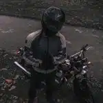 a person sitting on a motorcycle next to a river