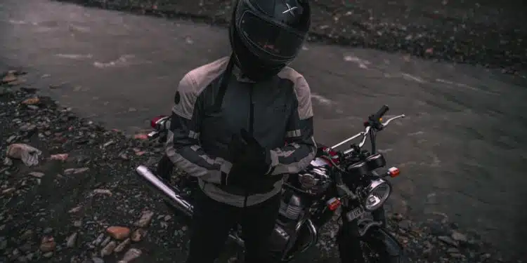 a person sitting on a motorcycle next to a river