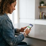 Jeune femme souriante utilisant une application de conduite à la maison