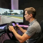 Pilote en tenue décontractée concentré sur un simulateur de conduite Assetto Corsa avec triple écran incurvé dans un studio de sim racing sombre